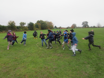 A group of children wearing winter coats in their school grounds, playing a game