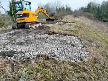 Patches of soil on a grassy path are being covered in rocks and rubble to prevent grass growing back in these areas. 