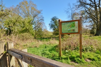 A sign for NWT Hoe Rough standing in a field on a sunny day