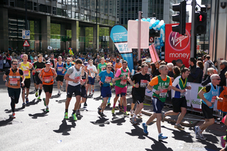 Runners on a sunny day in Canary Wharf take part in the London Marathon