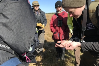 A man shows a group of people a slow worm