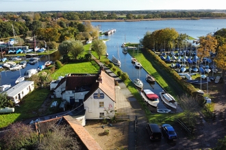 An aerial view of a broad jetty filled with boats, with buildings clustered around the edge