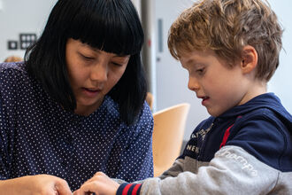 Alice Lee helping a child make a mobile