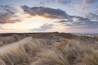 Sand dunes at Holme Dunes, under a cloudy sky at sunset