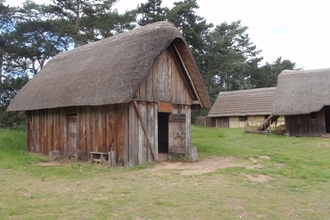 Several small thatched and timbered buildings in a Suffolk field