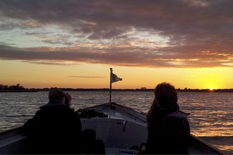 Passengers looking out from a boat at dawn at Hickling Broad
