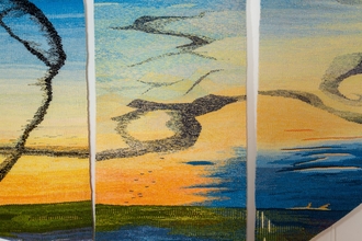 Vividly coloured tapestry showing flocks of bird flying close together and making patterns in the sky.