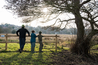 Our youth engagement officer and two young wilder wardens peering over a fence at Sweet Briar. 