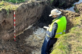 Tim Holt-Wilson standing in a pingo trench cut taking notes