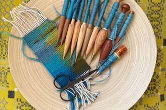 a selection of tapestry weaving equipment on a cream coloured mat