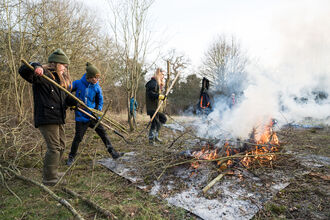 A group of young people next to a bonfire doing practical conservation work