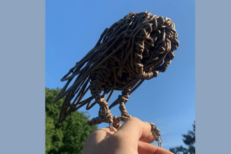 A willow sculpture of a barn owl perched on a hand