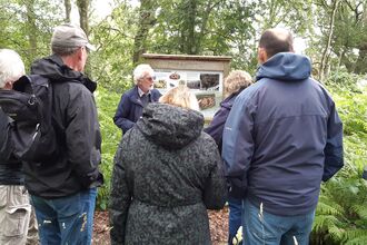 A group of people wearing waterproof coats on a guided walk at Hoe Common