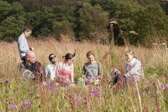 a group of people having a picnic in a wildflower meadow
