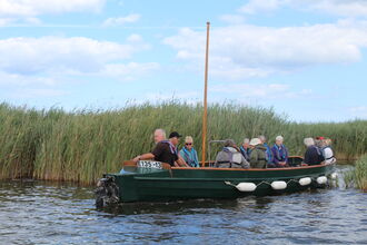 A group of people enjoy a boat trip across Hickling Broad