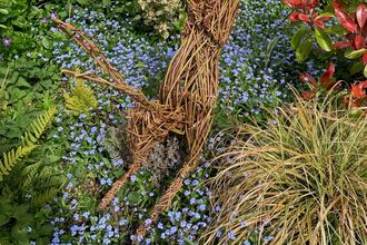 A willow woven leaping hare in a colourful garden