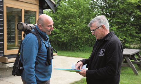 A member of staff showing a visitor directions on the reserve outside Hickling visitor centre