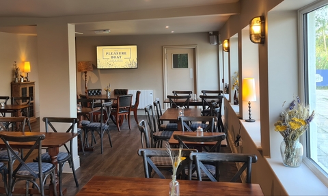 Tables, chairs, warm lamps and flowers inside the Pleasure Boat Inn.