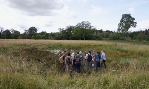 A group gather around an excavated pingo pond.