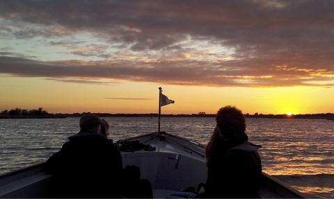 Passengers looking out from a boat at dawn at Hickling Broad