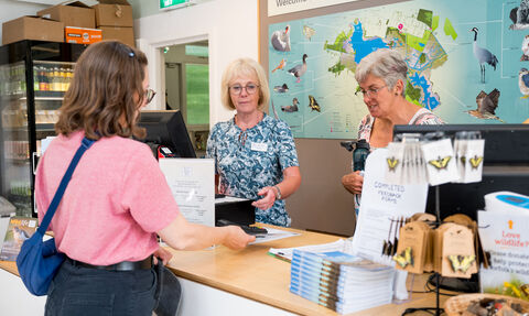 A visitor paying at the tills, at Hickling visitor centre. 