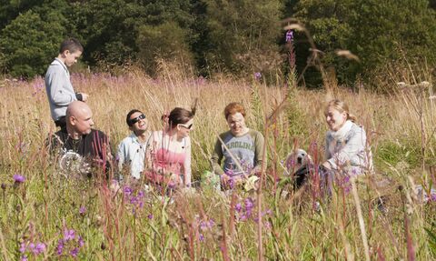 a group of people having a picnic in a wildflower meadow
