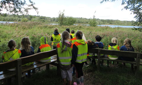 A group of primary school children in high-vis looking out over a nature reserve. 
