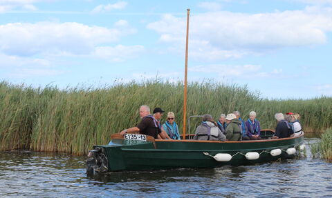 A group of people enjoy a boat trip across Hickling Broad