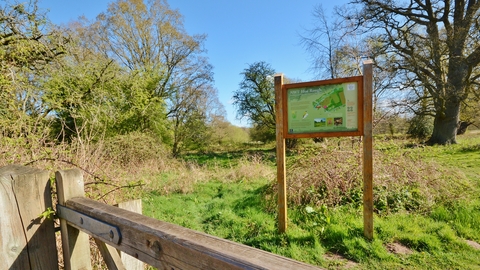 A sign for NWT Hoe Rough standing in a field on a sunny day