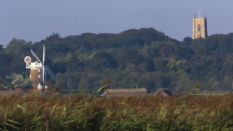 Cley marshes, with a windmill and church in the background, on a sunny day