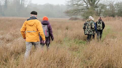 Four people walking through a field in winter