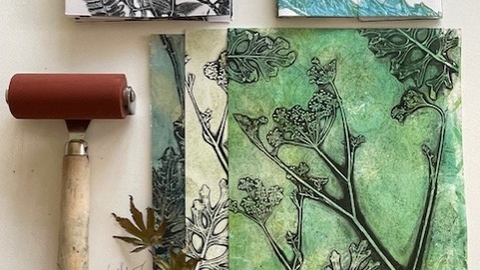 A gel print made from leaves alongside two smaller prints and a small hand roller