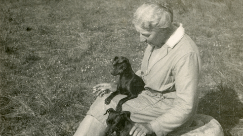 Picture of photographer Emma Turner sitting on the grass with two dogs.