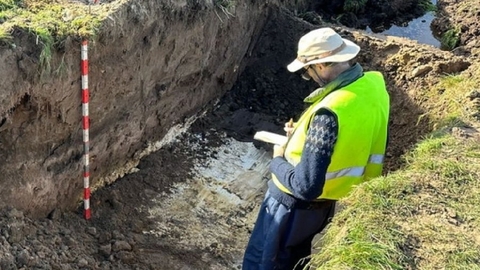 Tim Holt-Wilson standing in a pingo trench cut taking notes