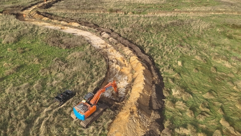 An aerial photograph of winding restoration works being carried out by an orange and blue digger in the foreground