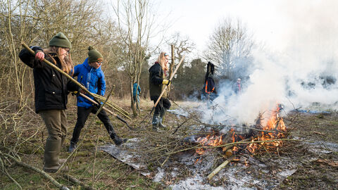 A group of young people next to a bonfire doing practical conservation work