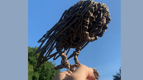 A willow sculpture of a barn owl perched on a hand
