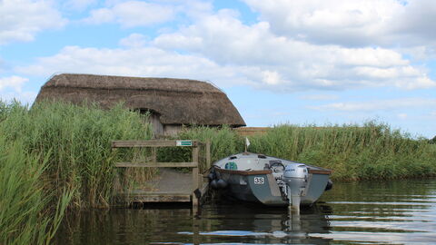 A boat moored outside a thatched hide