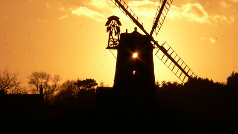 Cley windmill and trees silhouetted against a golden sunset