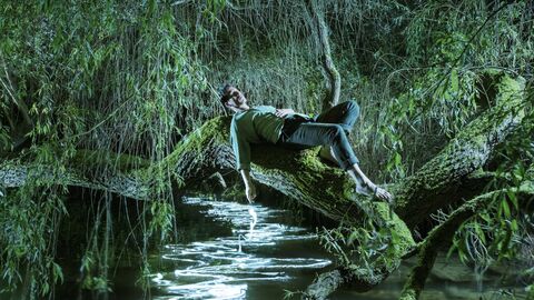 An album cover showing Sam Lee reclining on a horizontal tree branch across a stream with sparkling white patterns on the water
