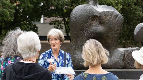 A group of people with a walk leader standing in front of a large sculpture