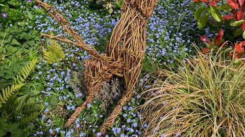A willow woven leaping hare in a colourful garden