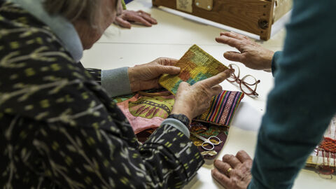 A workshop showing weavers working on small coloured tapestries