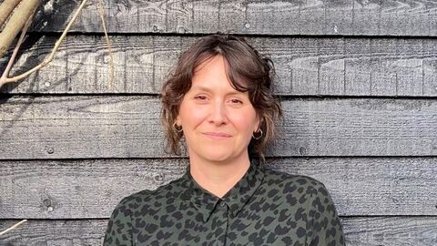 A head and shoulders photo of Professor Johanna Forster wearing a black and grey patterned shirt and smiling at the camera