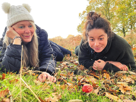 Two women look delighted as they spot a fly agaric