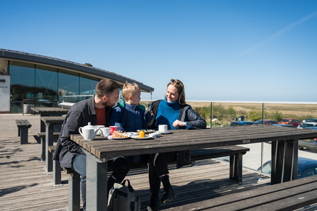 a family sitting on a picnic bench outside the Cley Marshes visitor centre