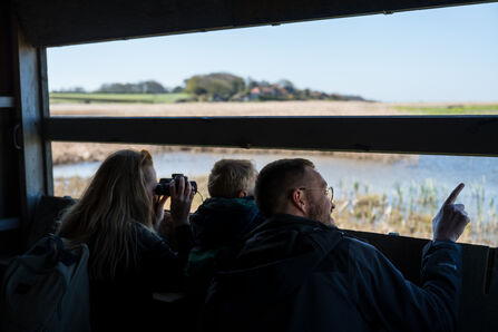 A young family peering out of a hide at Cley. 