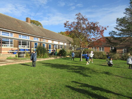 Primary school children running around a school field on a sunny day