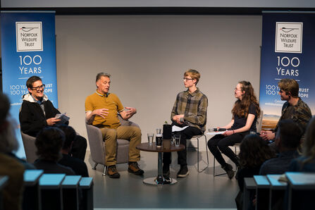 A panel of five people, including three young people, conducting an interview on stage.