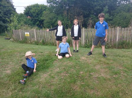 A group of school children posing on a patch of grass which will be made into a meadow